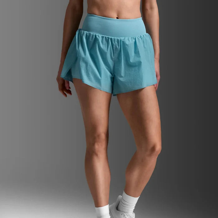 Person wearing light blue athletic shorts and white sneakers on a gray background
