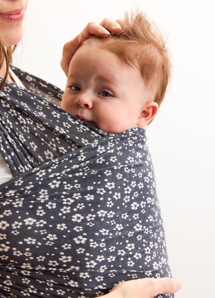 Navy blue maternity wrap with white ikat bloom pattern holding baby close.