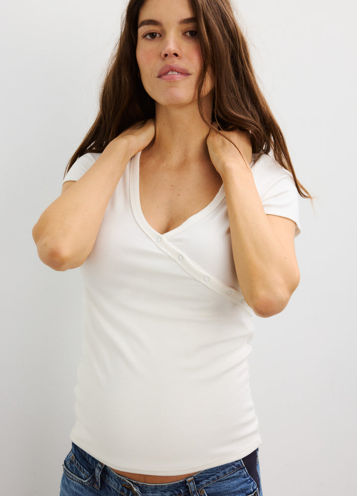 Cream-colored ribbed maternity wrap top with short sleeves and soft, stretchy fabric designed for pregnancy comfort.