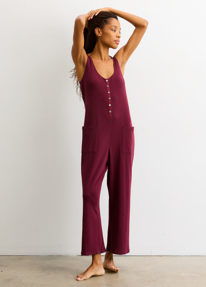 Sleeveless maternity jumpsuit in deep burgundy with button-front detail and relaxed wide-leg pants.