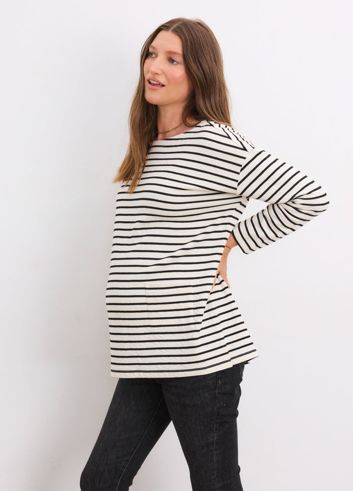 Black and ivory striped long-sleeve maternity top with bateau neckline worn by pregnant woman.
