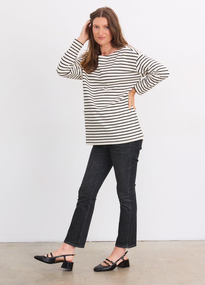 Pregnant woman wearing black and ivory striped maternity bateau top with long sleeves and black cropped pants.