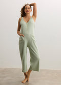 Light green sleeveless ribbed maternity jumpsuit with buttons and wide legs.
