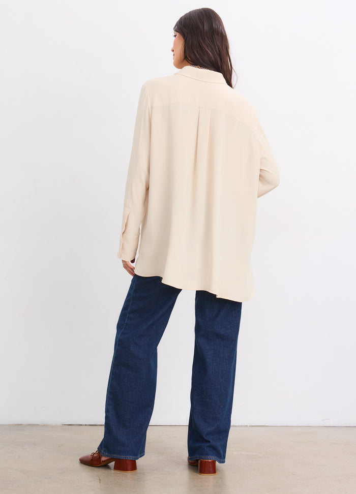 Pregnant woman wearing sandshell maternity Celeste Drapey Buttondown with long sleeves and relaxed back.