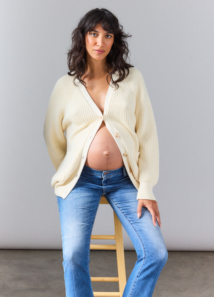 Ivory maternity cardigan with buttons, worn open over pregnant belly, paired with blue jeans.