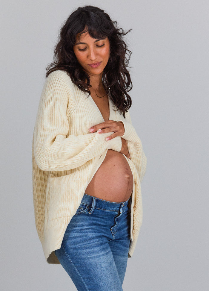 Ivory oversized knit cardigan with long sleeves worn open over a pregnant belly and blue jeans.