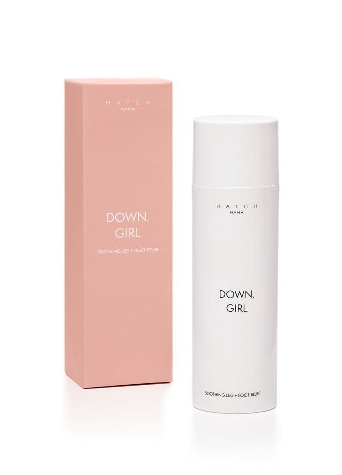 White cylindrical bottle with minimal black text beside tall rectangular pink box labeled Down Girl and maternity essentials.