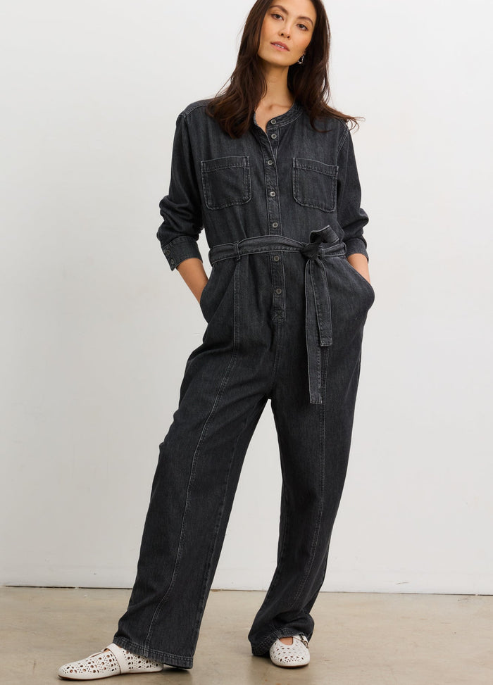 Washed black maternity denim jumpsuit with long sleeves, button front, belted waist, and relaxed fit for pregnant women.