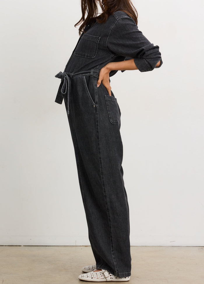 Washed black maternity denim jumpsuit with adjustable waist tie and rolled sleeves on pregnant model.