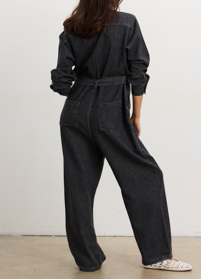 Dark gray denim jumpsuit with long sleeves, relaxed fit, and cinched waist, styled for maternity.