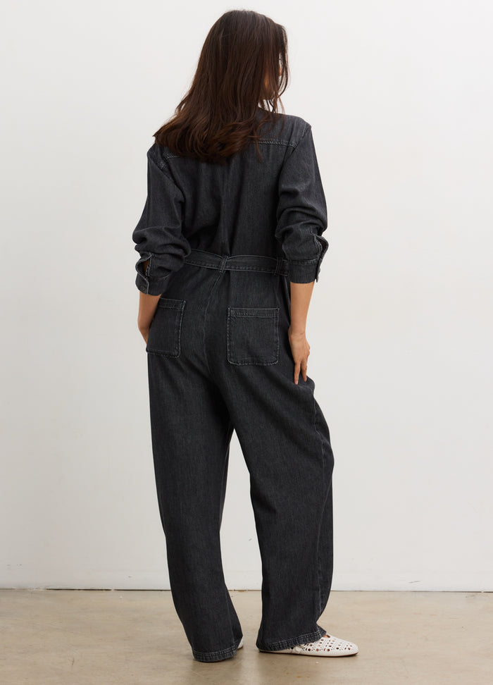 Black denim jumpsuit with long sleeves, relaxed fit, and back patch pockets, styled for maternity.