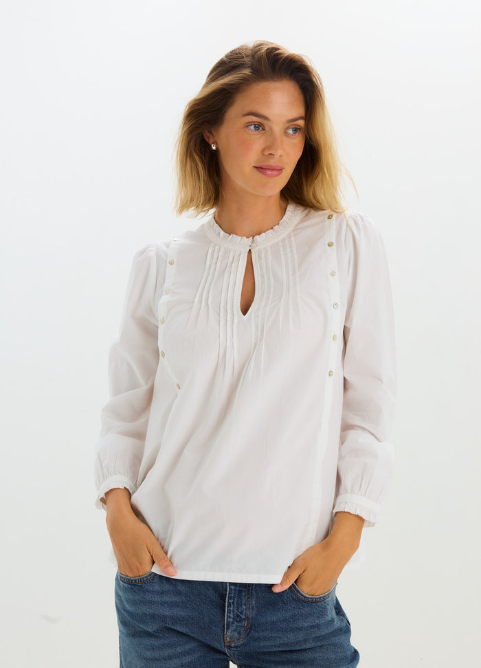 White maternity nursing blouse with long sleeves, keyhole neckline, and delicate pleated detailing.