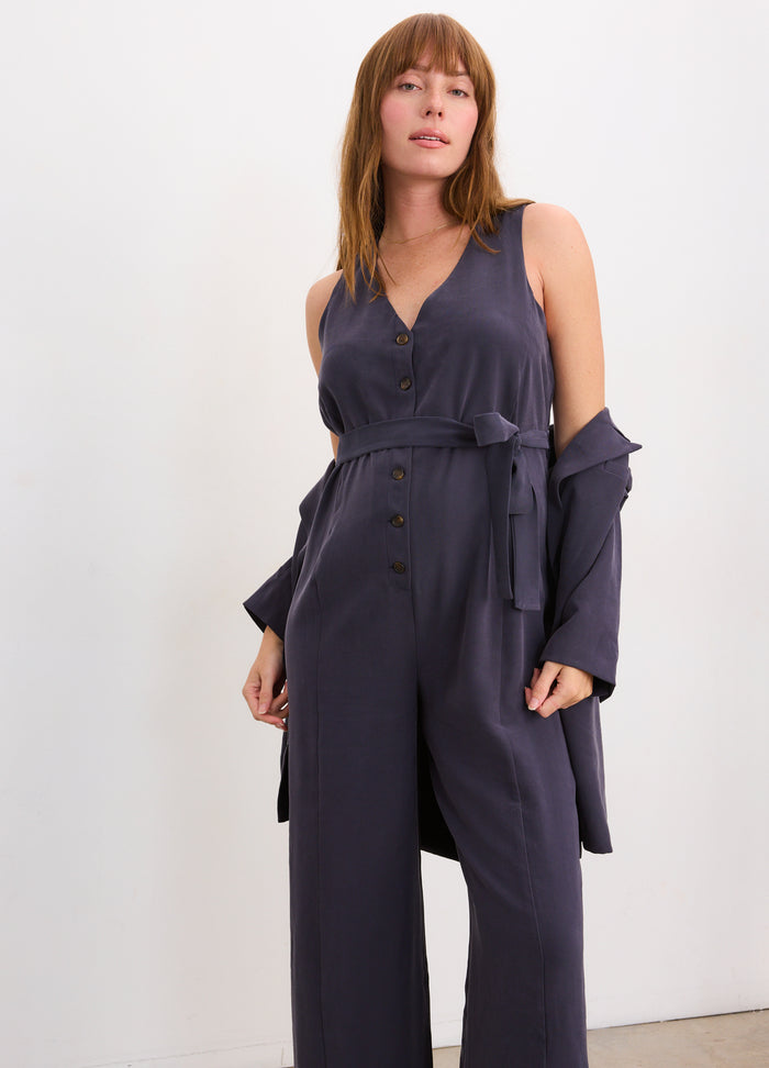 Slate blue sleeveless maternity jumpsuit with V-neck and waist tie, styled for pregnant women.