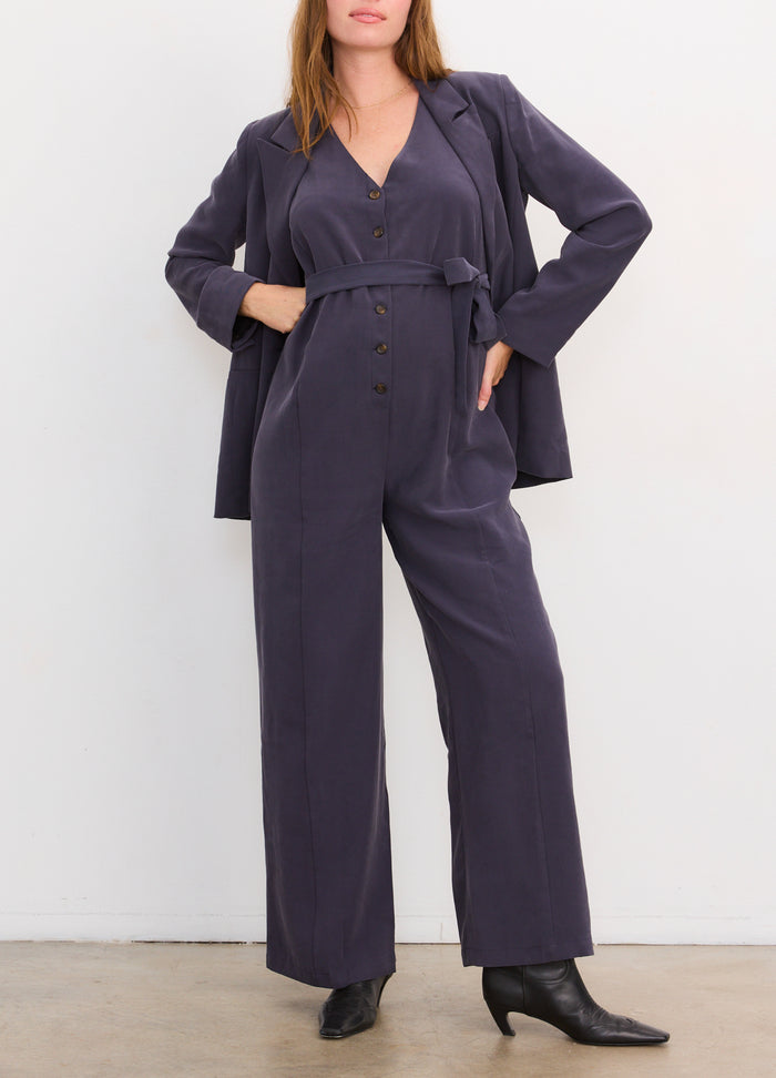 Navy blue maternity jumpsuit with long sleeves, button-up front, and wide-leg pants.