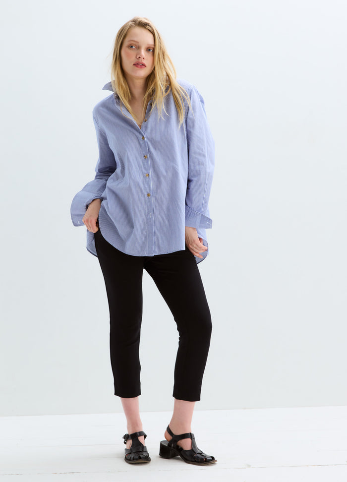 Black cropped maternity stretch suit pants with a slim fit on a model wearing a blue striped shirt.