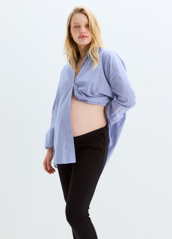 Black stretchy maternity suit pants with a soft, supportive waistband modeled with a light blue open shirt.