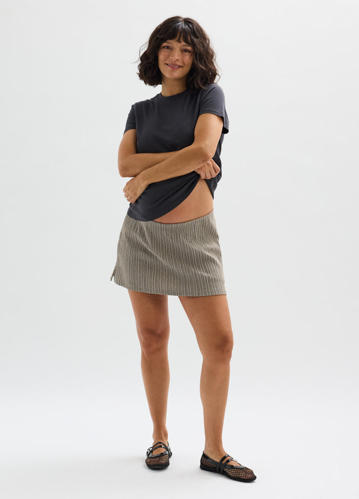 Beige ribbed maternity skort with soft elastic waistband styled with black fitted short-sleeve top and black sandals.