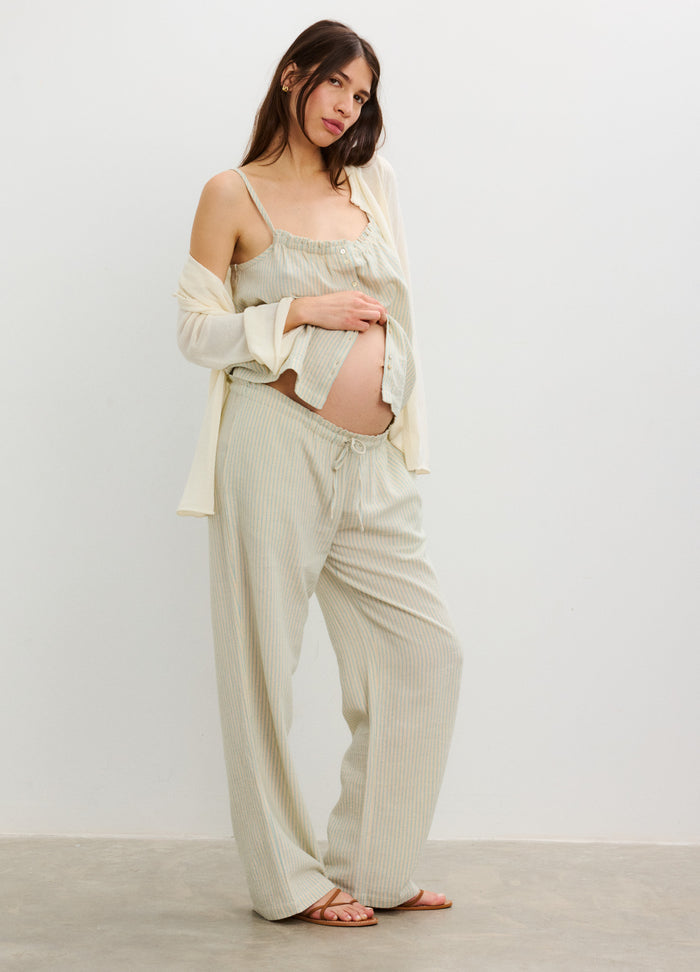 Light beige loose maternity pants with a wide elastic waistband, relaxed fit, worn by a pregnant woman.