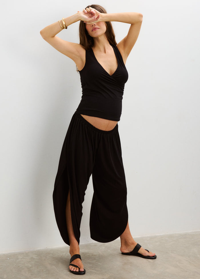 Black maternity pants with wide legs and high, stretchy waistband designed for pregnant bellies, worn with a black tank top.