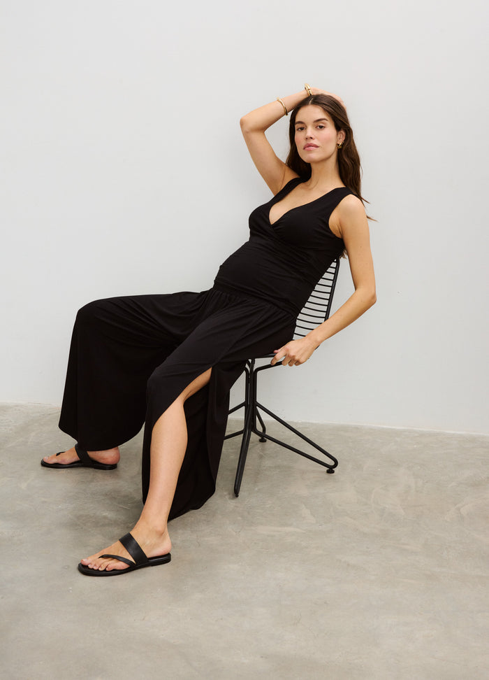 Black wide-leg maternity pants with side slits, worn with a fitted sleeveless black top.