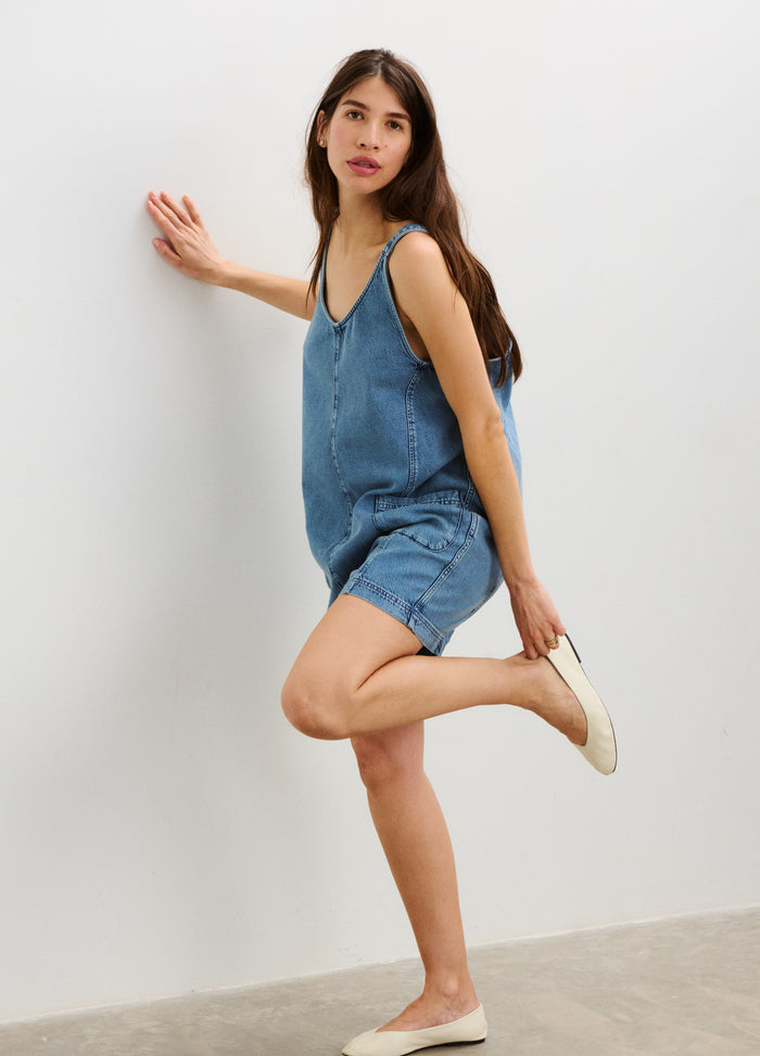 Blue denim sleeveless maternity romper with adjustable straps and relaxed shorts fit.