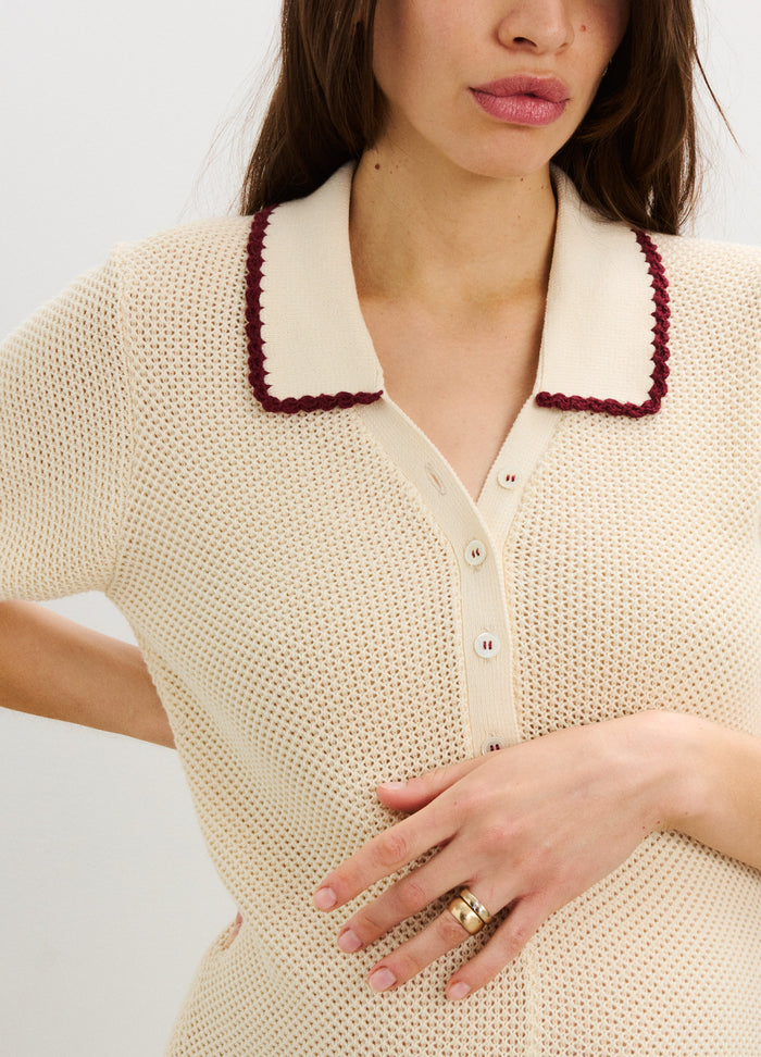 Cream knit nursing romper with short sleeves, button front, and burgundy-trimmed collar designed for maternity.
