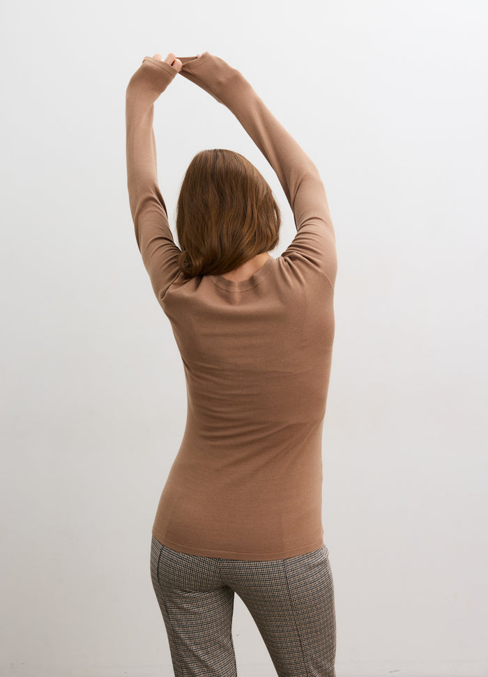 Light brown ribbed knit long sleeve tee with fitted body and crew neckline, worn by woman stretching with arms raised.